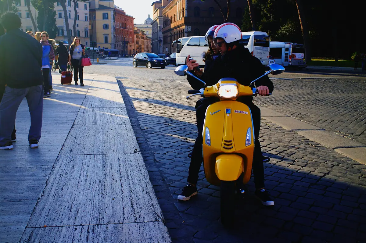 Coppia in Vespa gialla per le strade di Roma