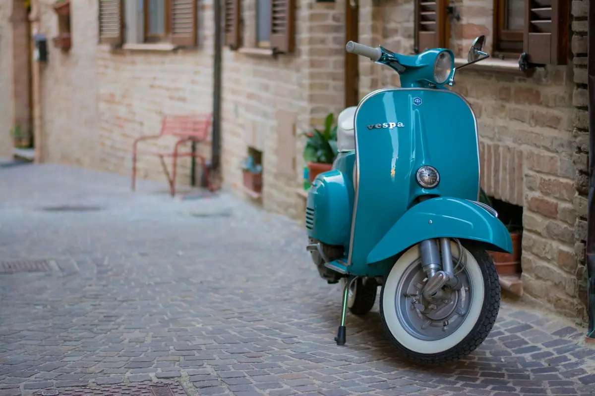 Vespa d'epoca verde acqua in un vicolo lastricato