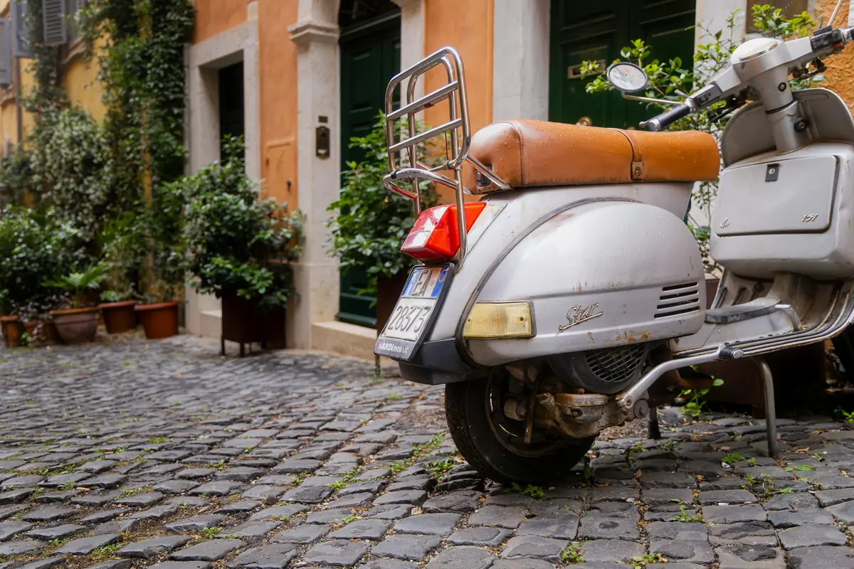Vespa parcheggiata sui sampietrini di una via del centro storico di Roma