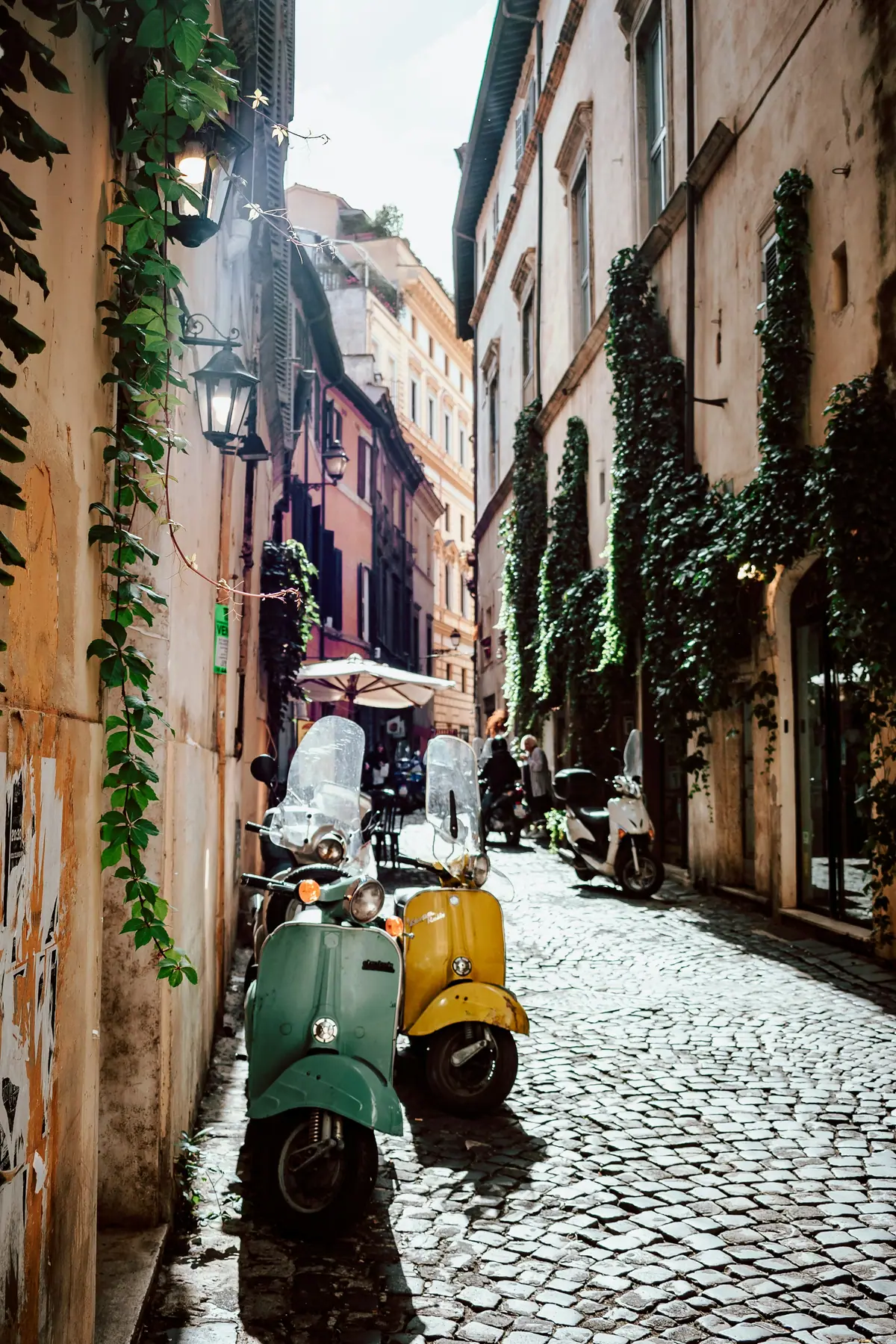 Due Vespe, verde e gialla, in un vicolo di sampietrini a Roma
